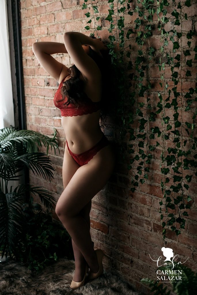 Bridal Boudoir Photo Inspiration in Sacramento by Carmen Salazar; brunette in red two piece lacey lingerie, full body against brick wall