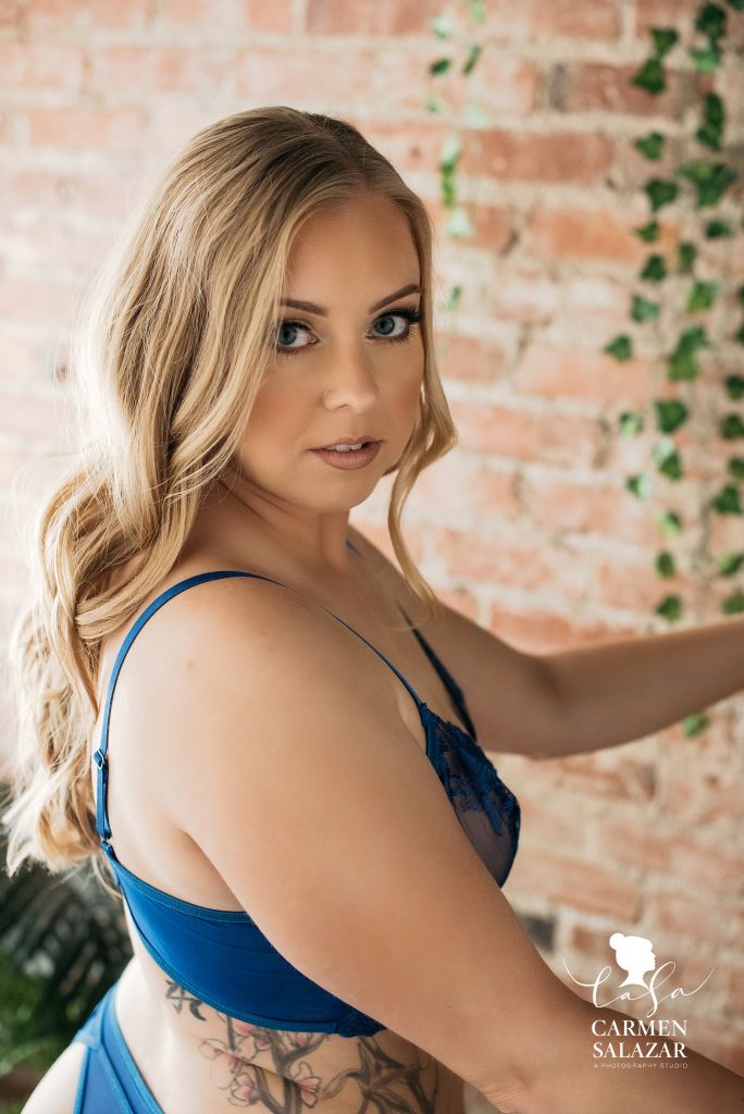 blonde woman in blue lingerie with brick backdrop; Boudoir Photography by Carmen Salazar