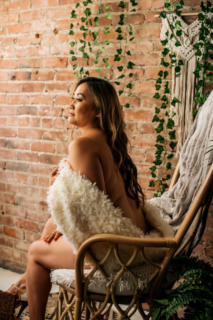 Sexy Boudoir Portrait, Topless woman covered in fur with brick backdrop, Carmen Salazar Photography
