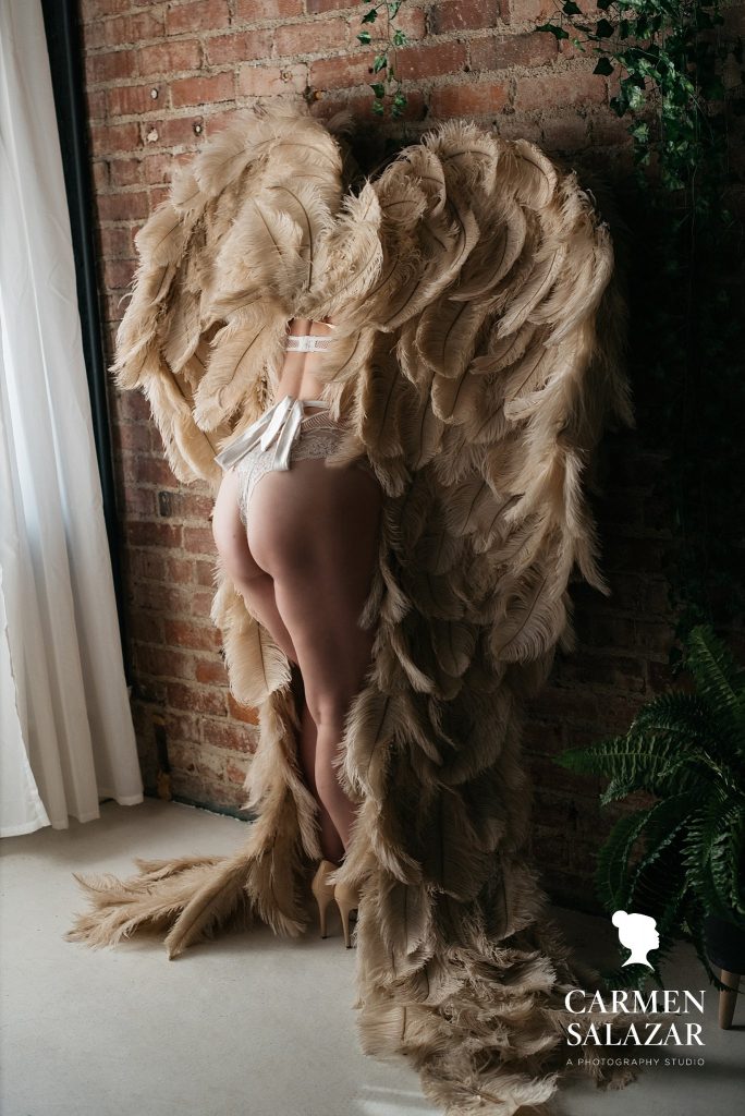 Woman in Angel Wings against a brick wall; Carmen Salazar Photography