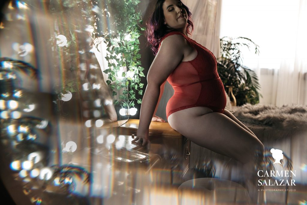 Plus sized woman in red lace bodysuit, boudoir photography repeat clients, photography by Carmen Salazar