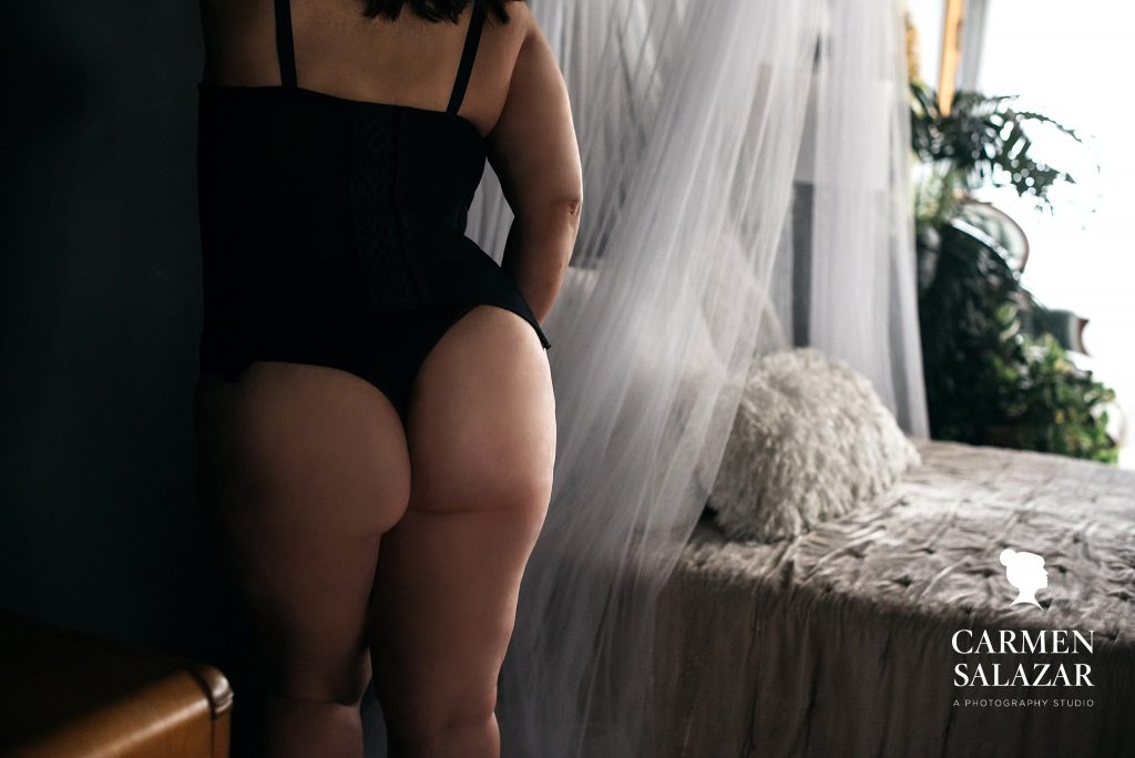 Woman's tushie in black lingerie with bed in background; photography by Carmen Salazar
