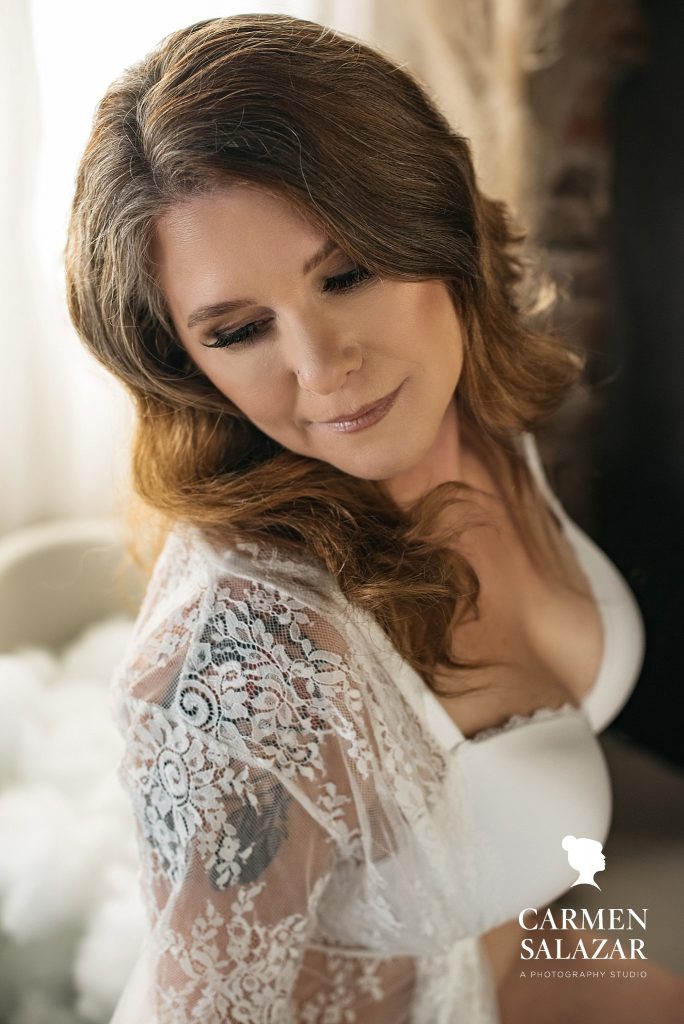 Never too old for boudoir photography woman in 50’s in white lingerie by tub; photography by Carmen Salazar