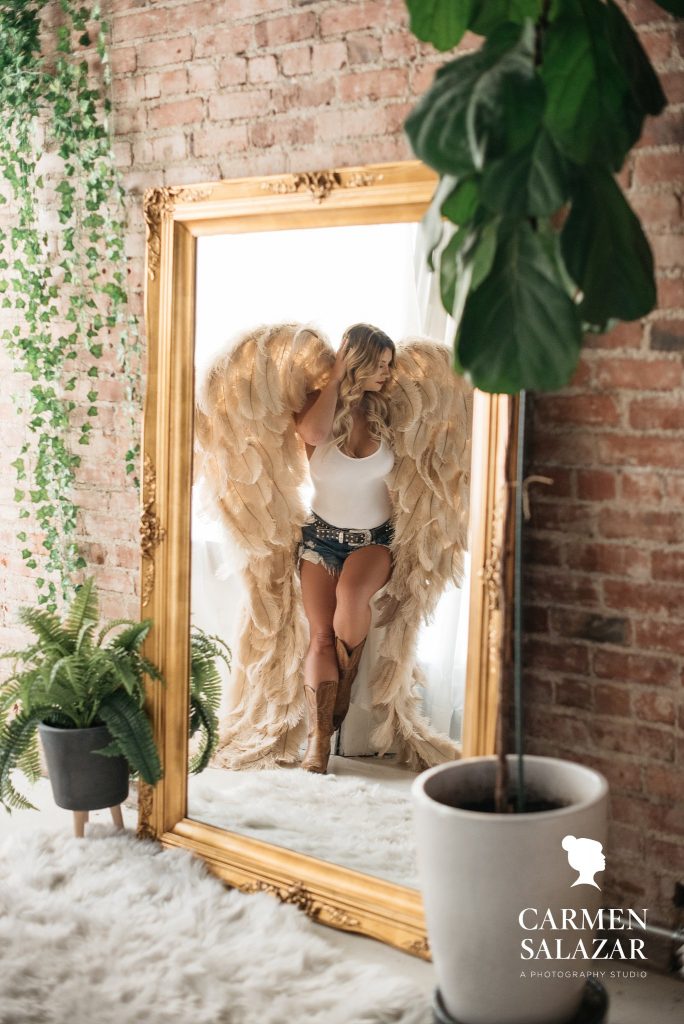 woman in white tank, jean shorts, cowboy boots and wings, girl next door boudoir, photography by Carmen Salazar
