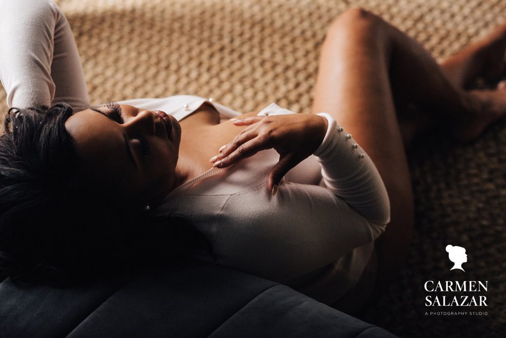 woman in white sweater leaning up against couch, boudoir photography by Carmen Salazar