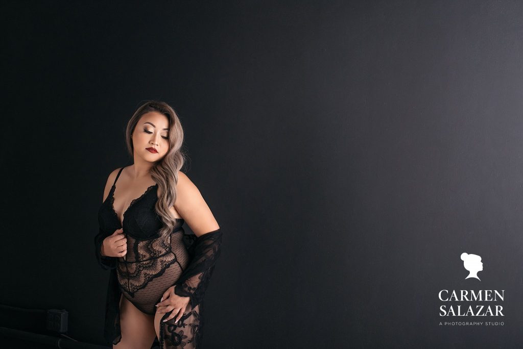 Woman in lacey black lingerie with black background, boudoir photography by Carmen Salazar