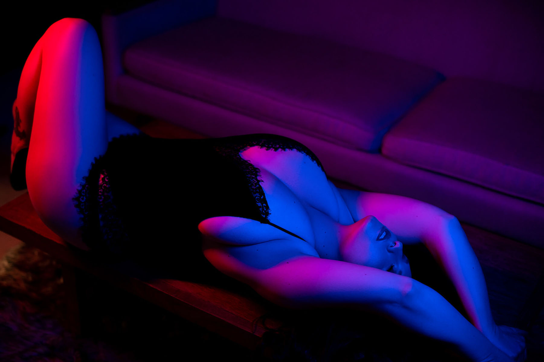 Blacklight boudoir portrait of woman posing in artistic lighting